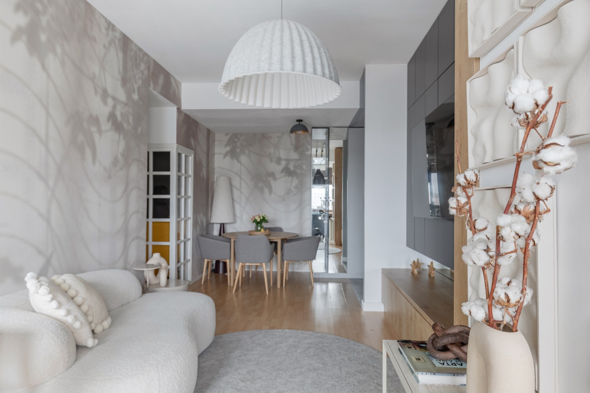 Living room designed by Maria: a bouclé sofa, a white dome pendant, leaf-shadow wallpaper and a round dining table